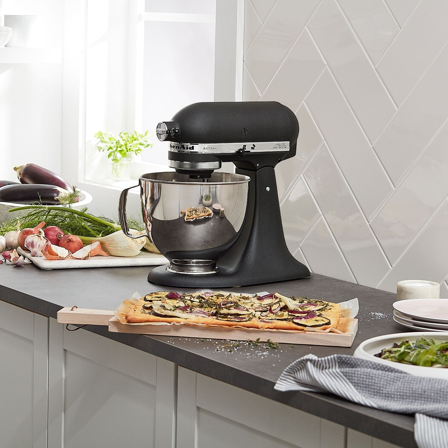 Black tilt-head stand mixer on counter with stainless bowl and paddle