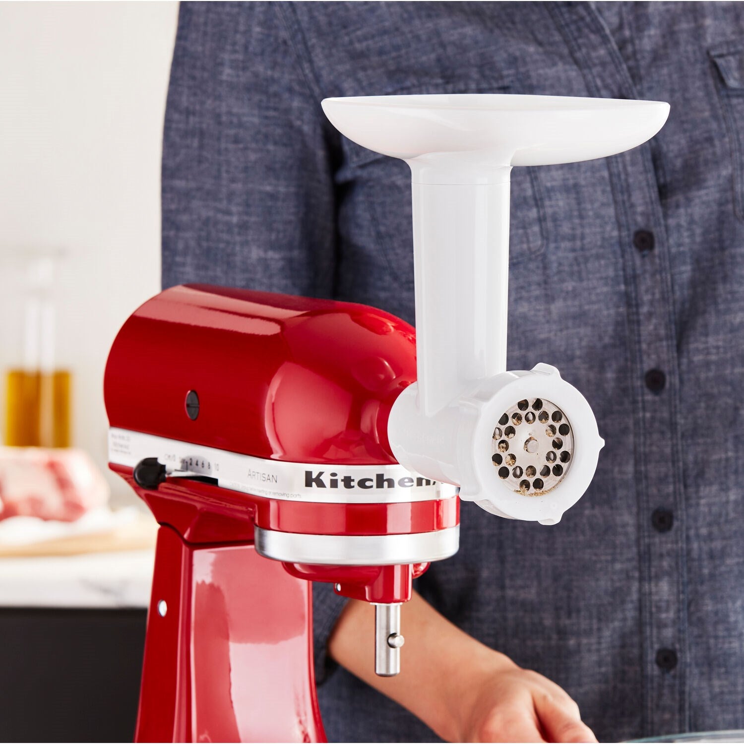 Close-up of food grinder attachment head with grinding plate and white pusher