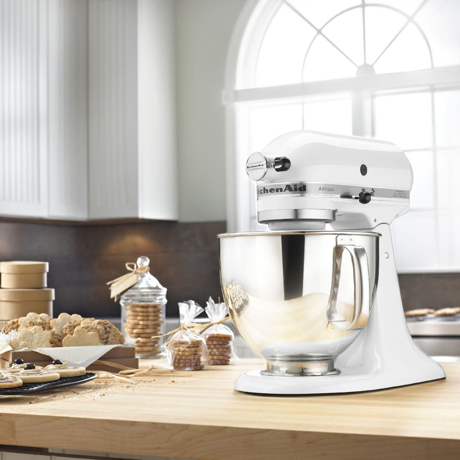 White KitchenAid tilt-head stand mixer on countertop with stainless mixing bowl.