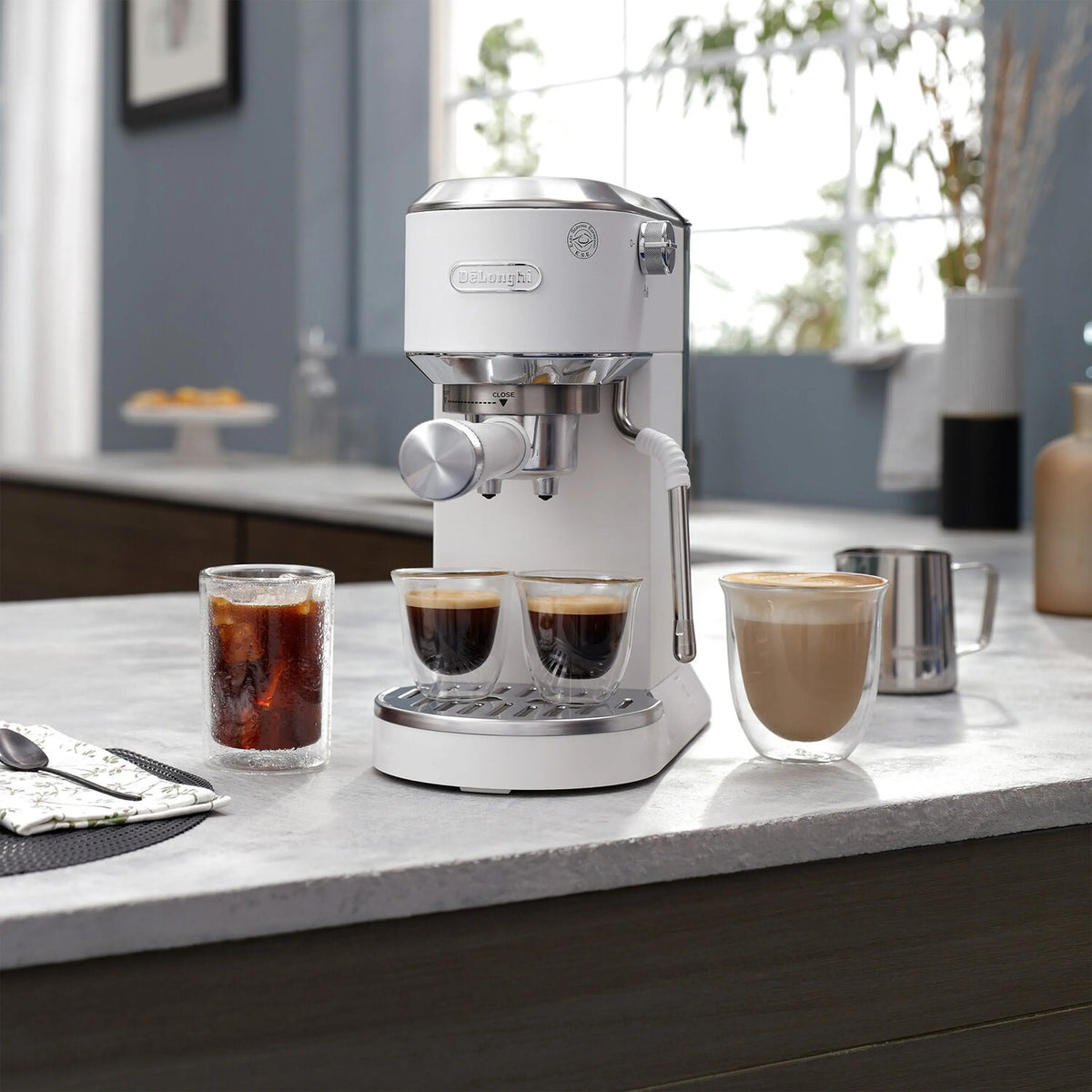 Countertop espresso machine with steam wand and three filled cups under the spouts