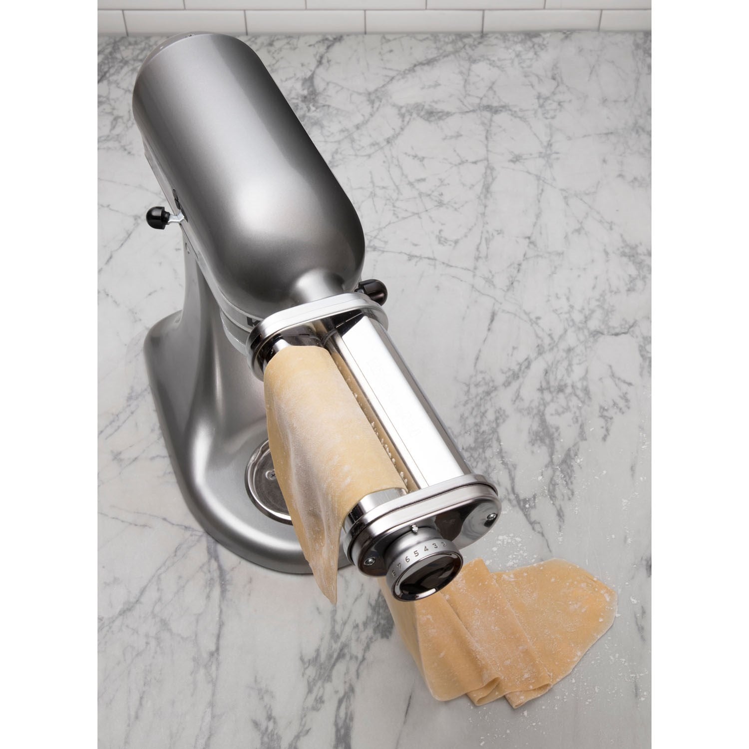 Metallic pasta roller attachment with golden dough sheet and round adjustment dial