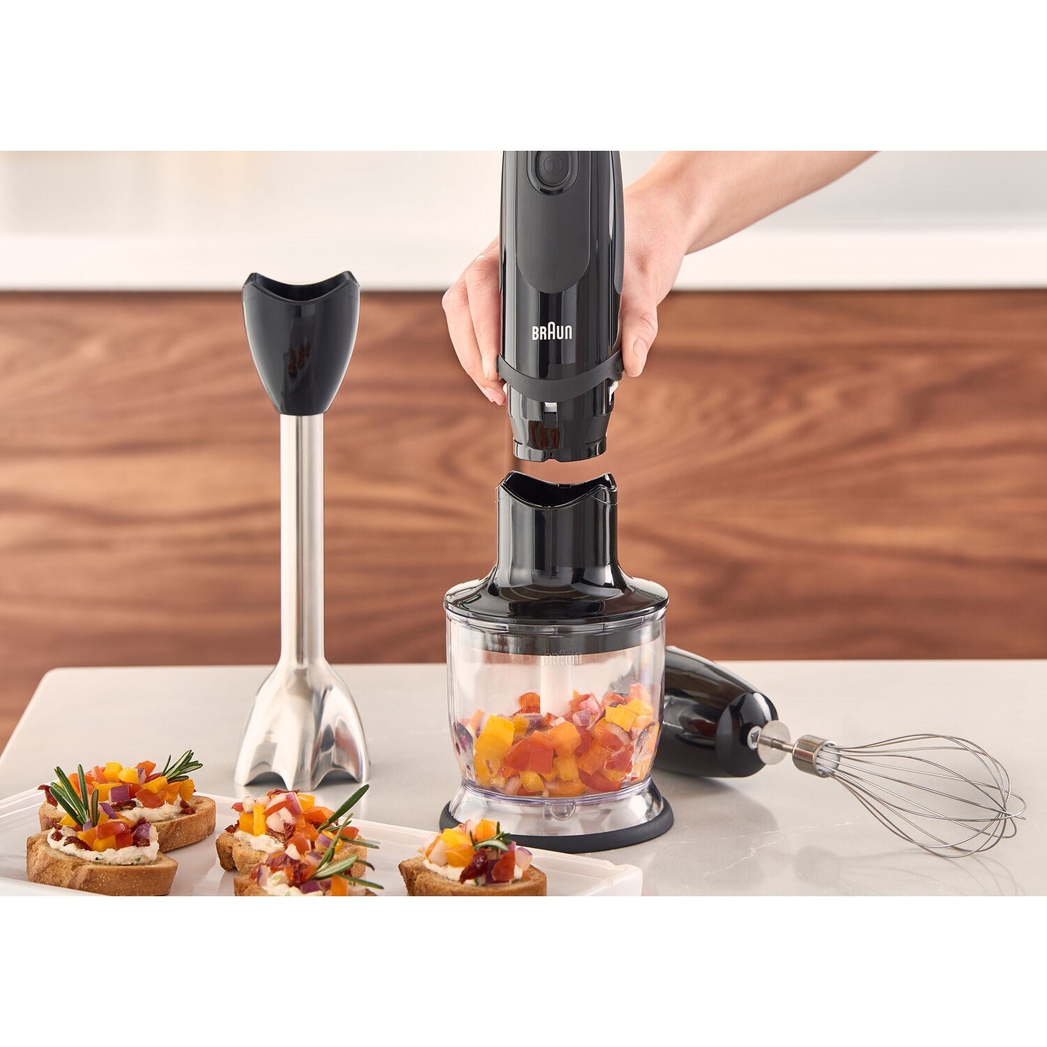 Black hand blender with chopper attachment and glass cup, for chopping ingredients.