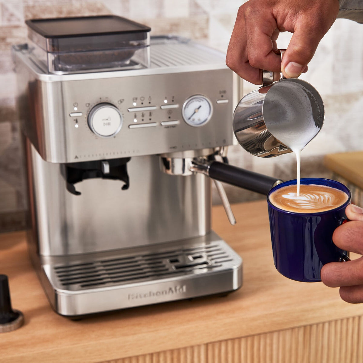 Stainless steel espresso machine pouring crema into a blue cup