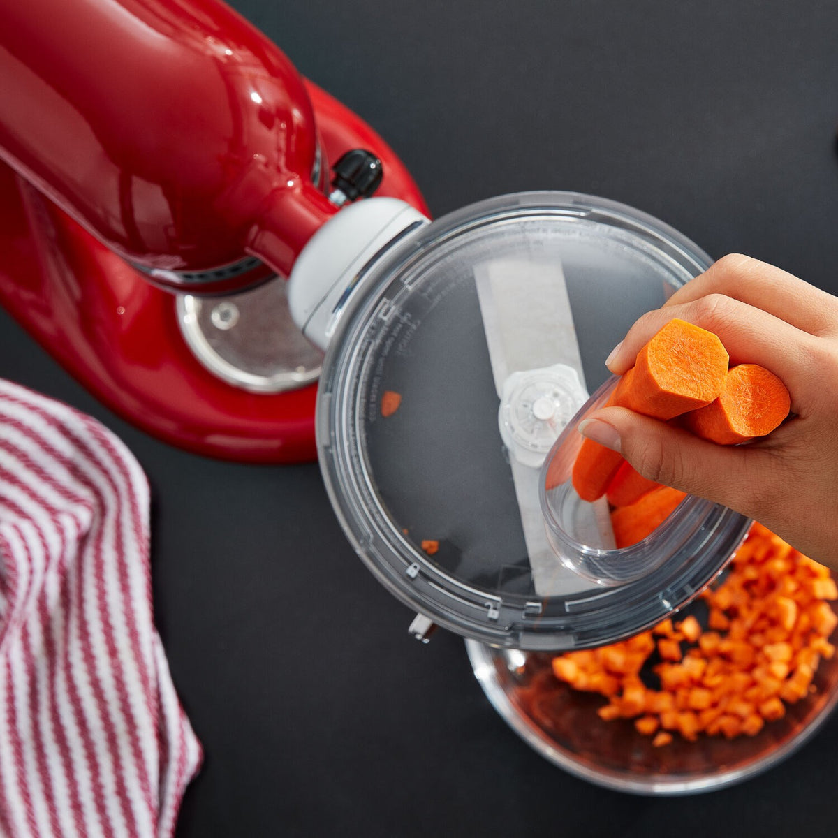 Hand adding orange food pieces into clear dicing attachment lid
