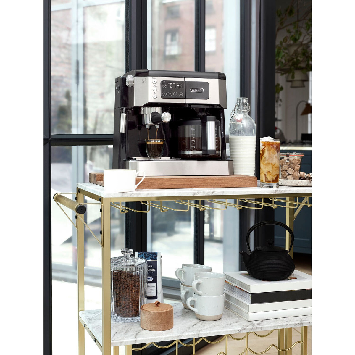De'Longhi espresso and drip coffee machine on appliance cart with glass and supplies