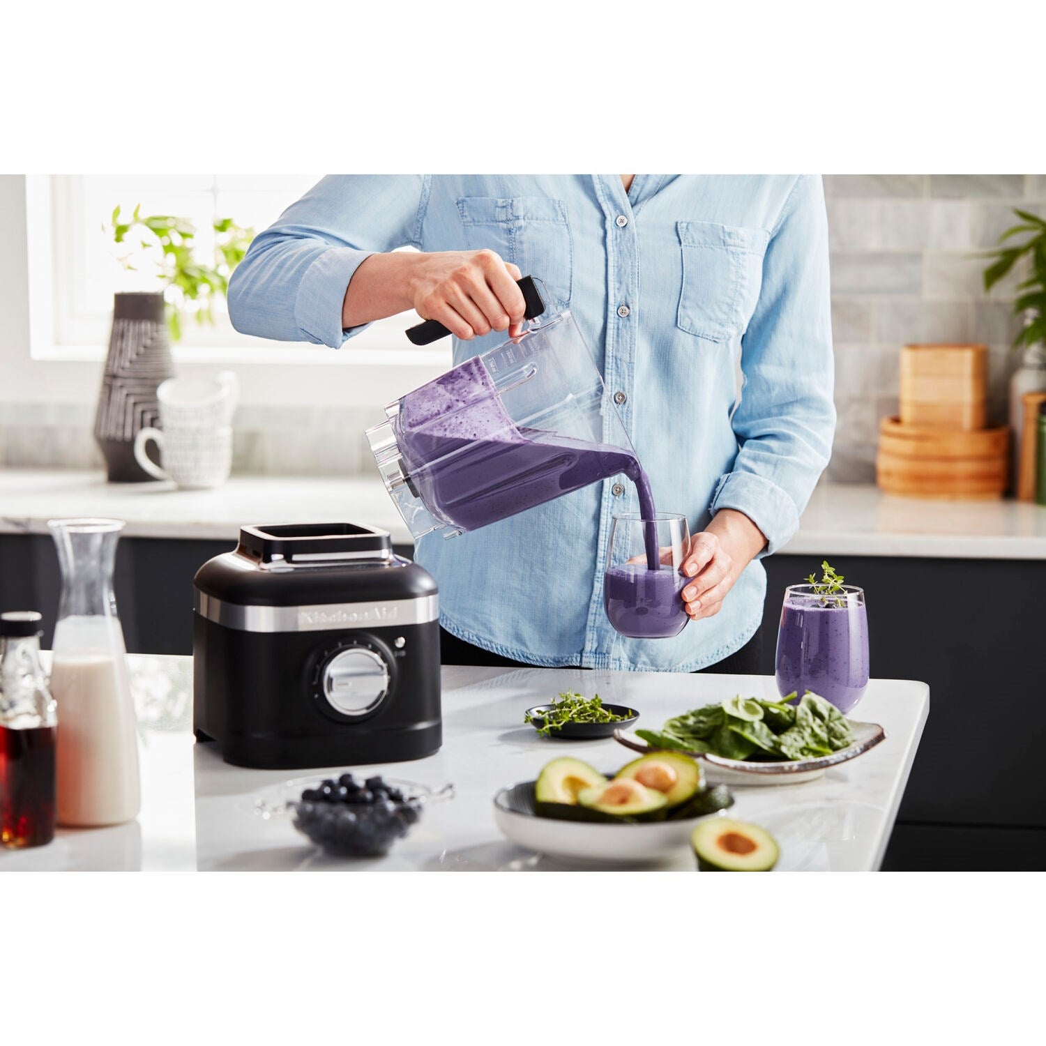 Black countertop blender with clear jar, used to blend purple ingredients