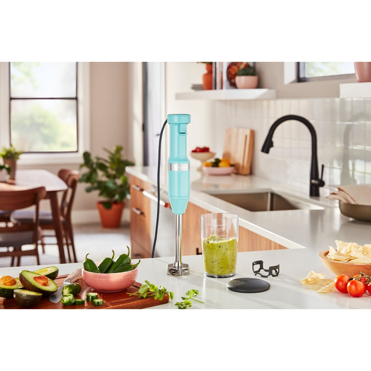 Immersion blender blending green ingredients inside a clear blending jar