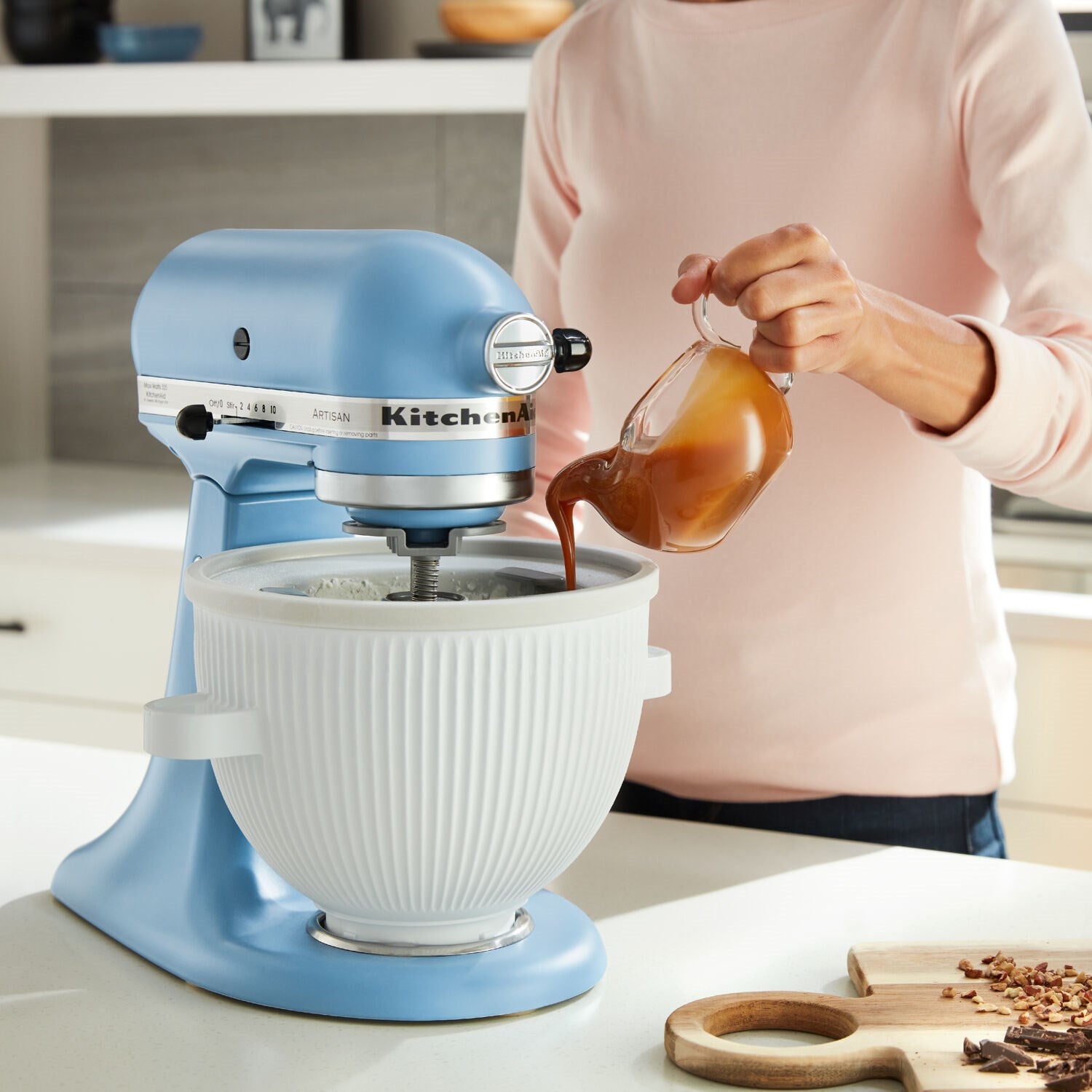 Blue tilt-head stand mixer with stainless bowl as batter is poured in
