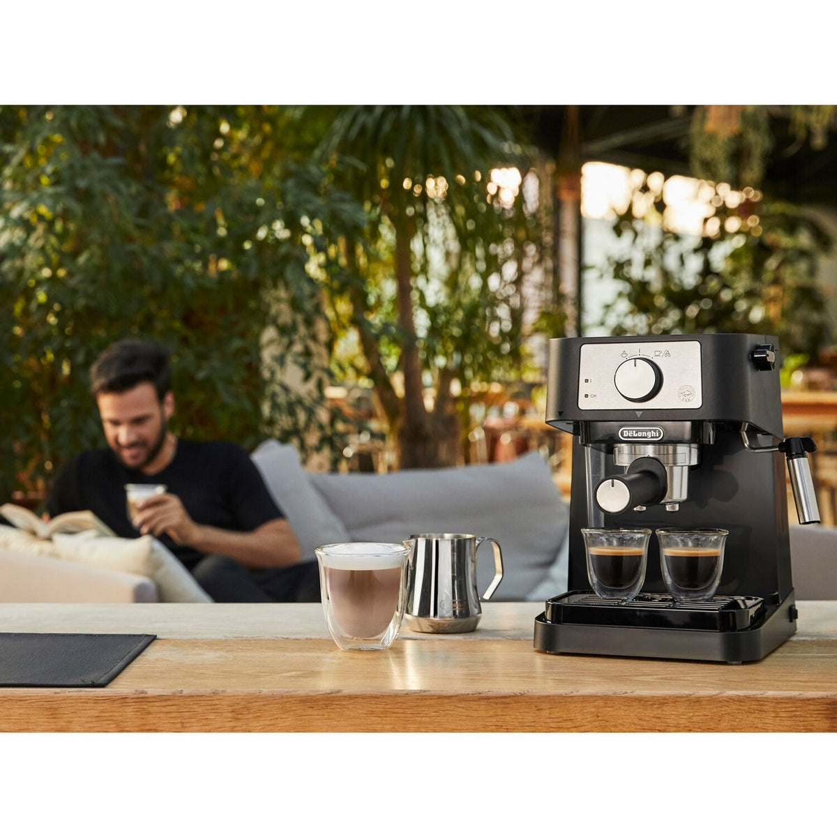 Black pump espresso machine on outdoor table with two cups