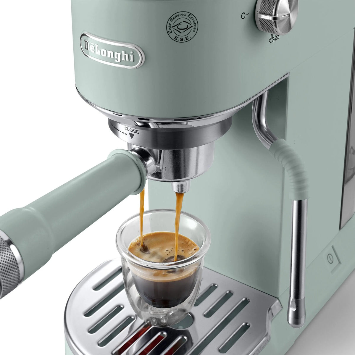 De'Longhi Dedica Duo espresso machine close-up, mint green, frothing wand pouring into cup