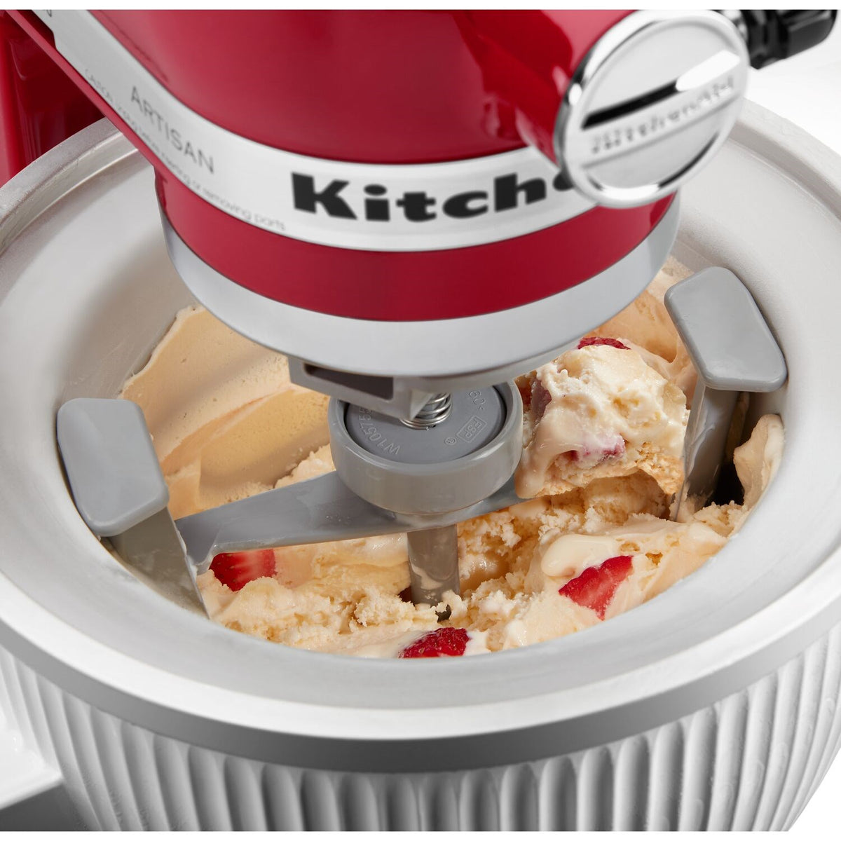 White ridged ice cream maker bowl filled with pale ice cream and fruit bits