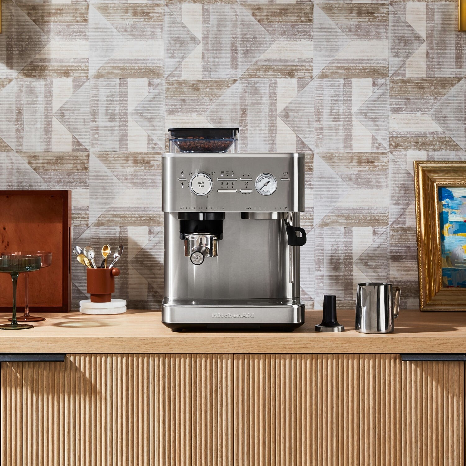 Stainless steel espresso machine with steam wand and milk pitcher on countertop