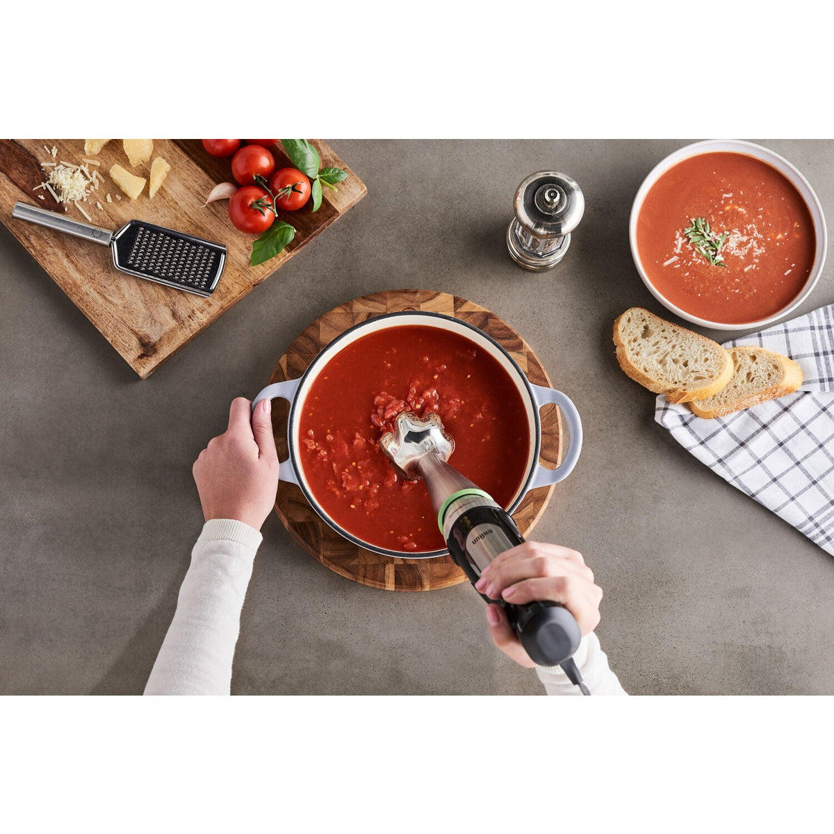 Braun hand blender blending a red soup in a pot