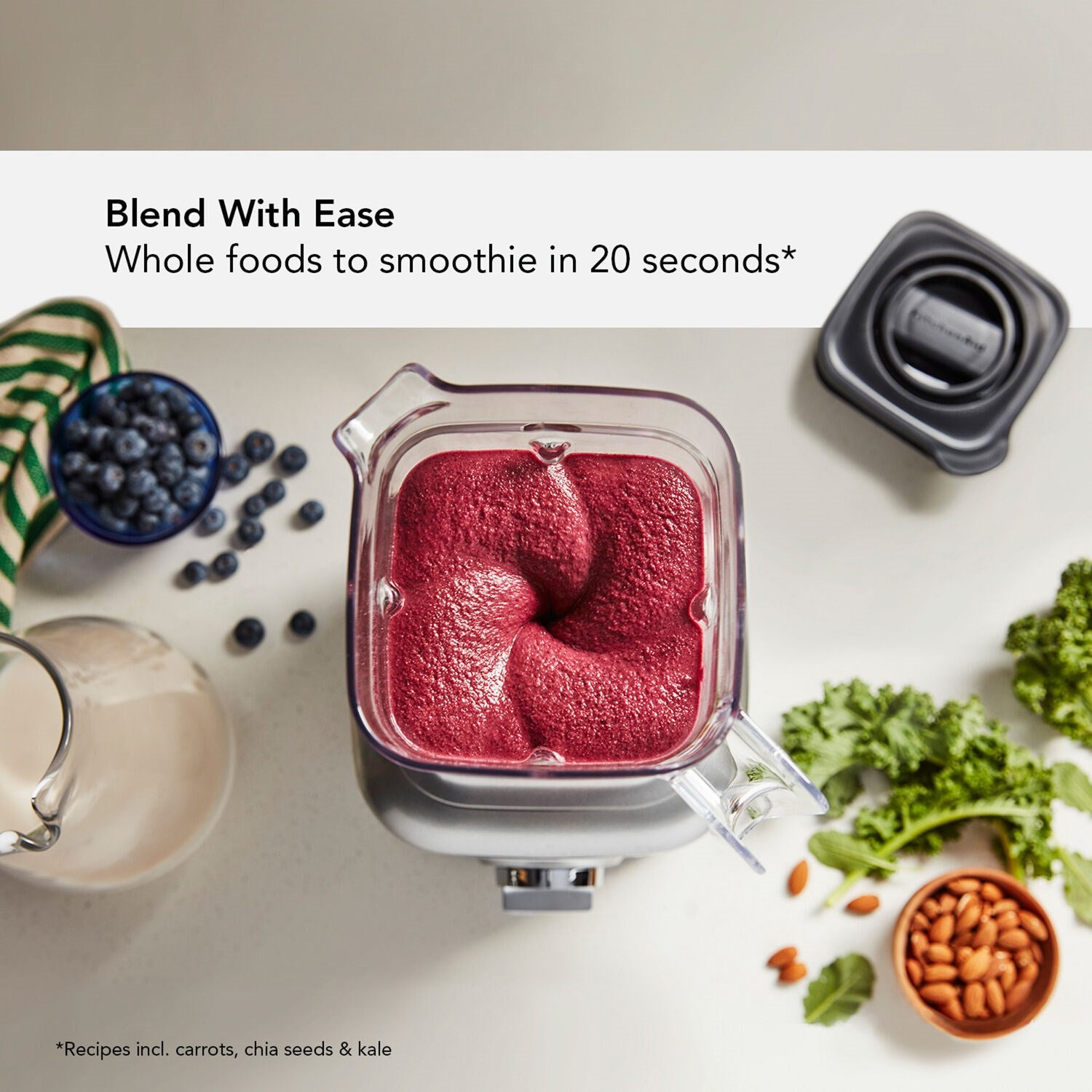 KitchenAid K400 blender with clear jar and red smoothie, jar positioned above cups