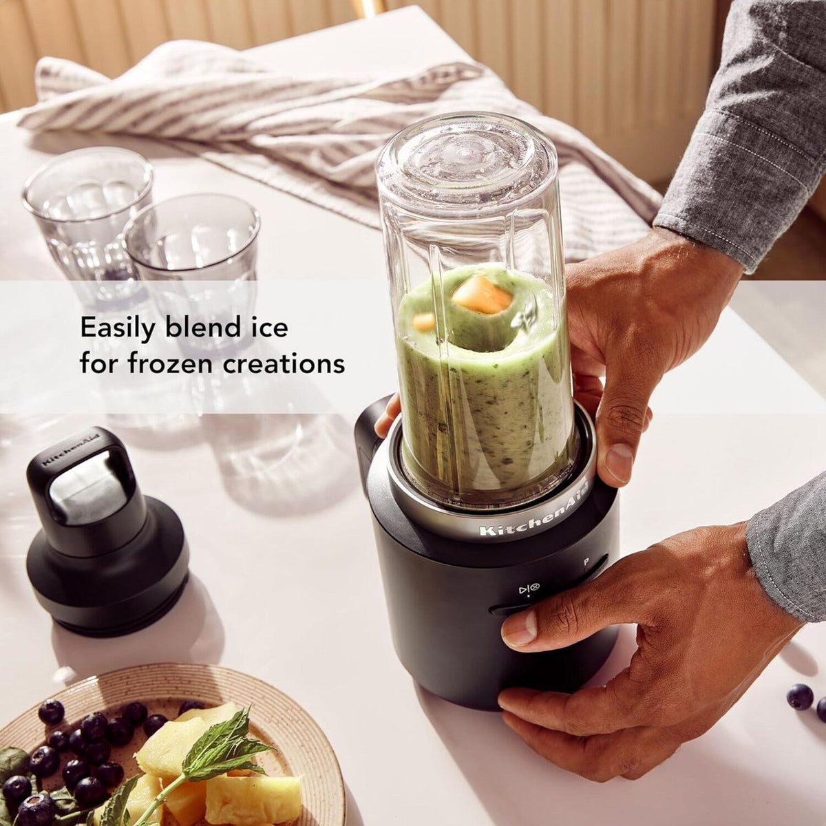 Black personal blender in use with clear jar filled with green smoothie