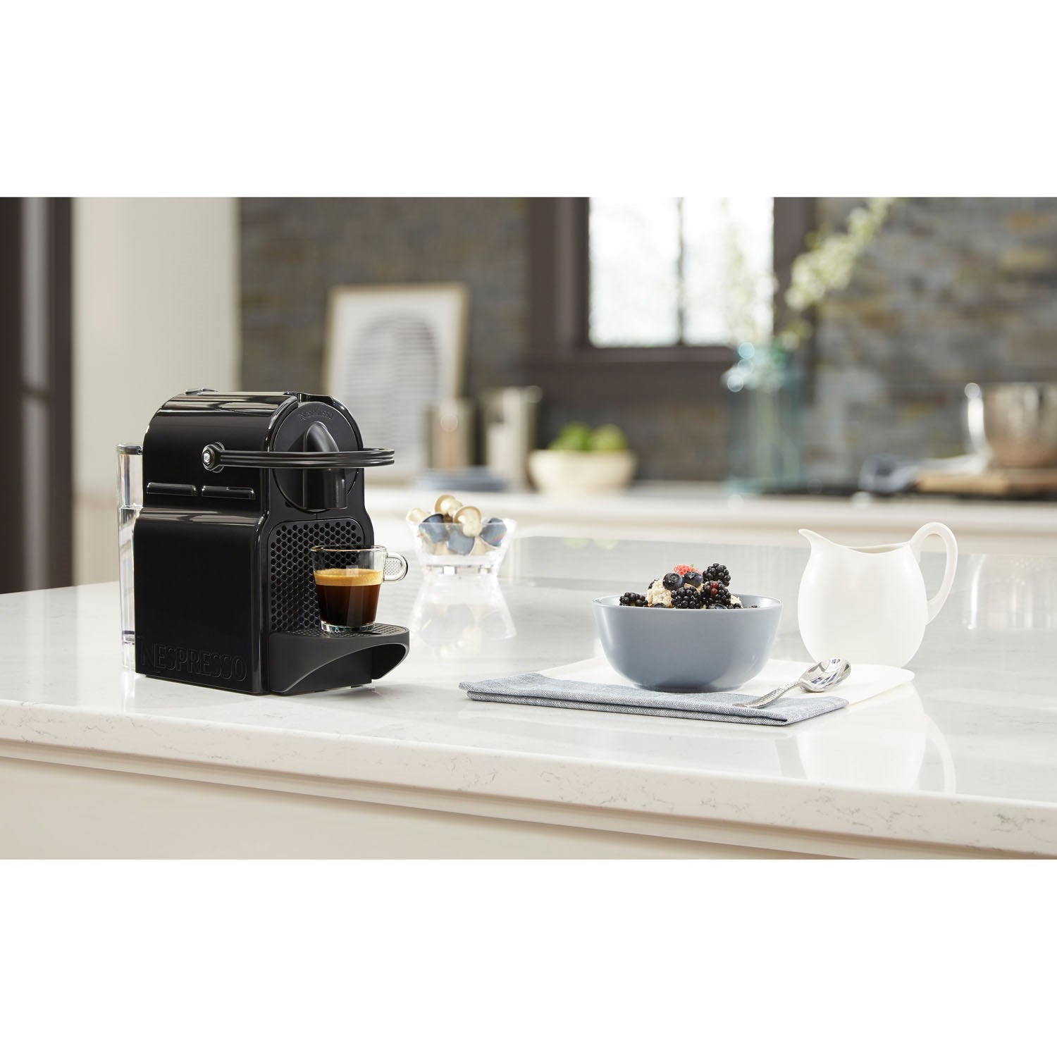 Black Nespresso espresso machine on kitchen countertop with coffee cup