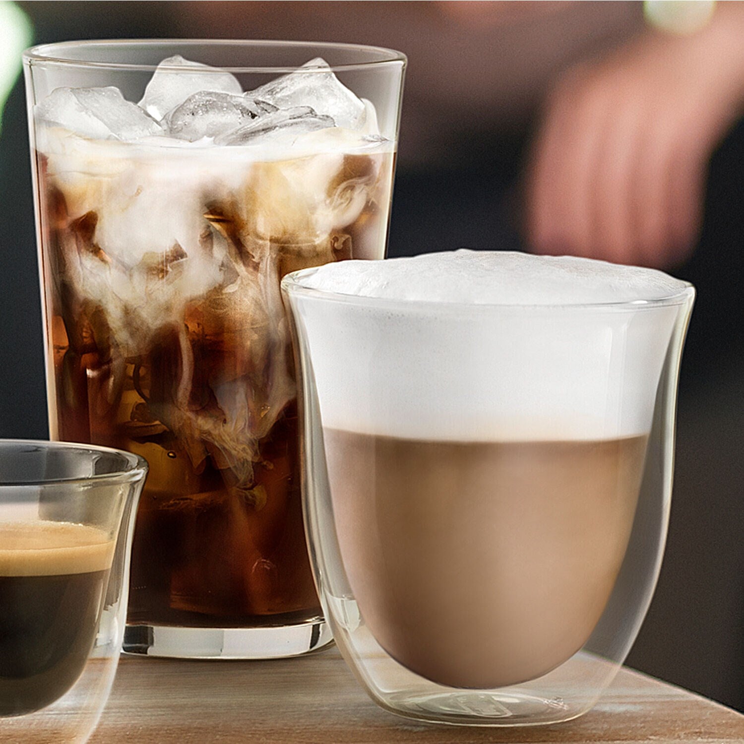 Two double-wall iced coffee glasses with ice and creamy foam, one in front