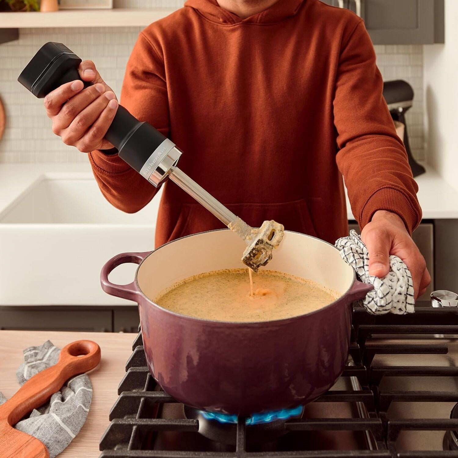 Cordless hand blender in black matte, blending batter in a saucepan.