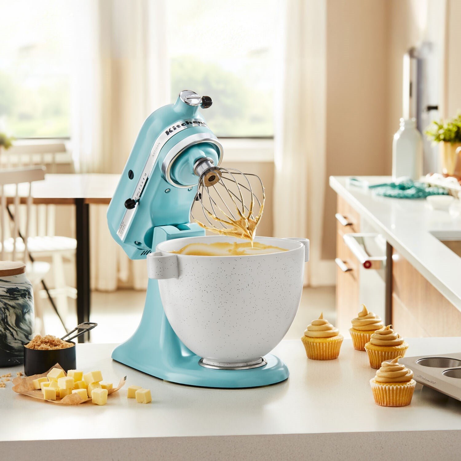 Mineral water blue tilt-head stand mixer whisking batter in stainless mixing bowl