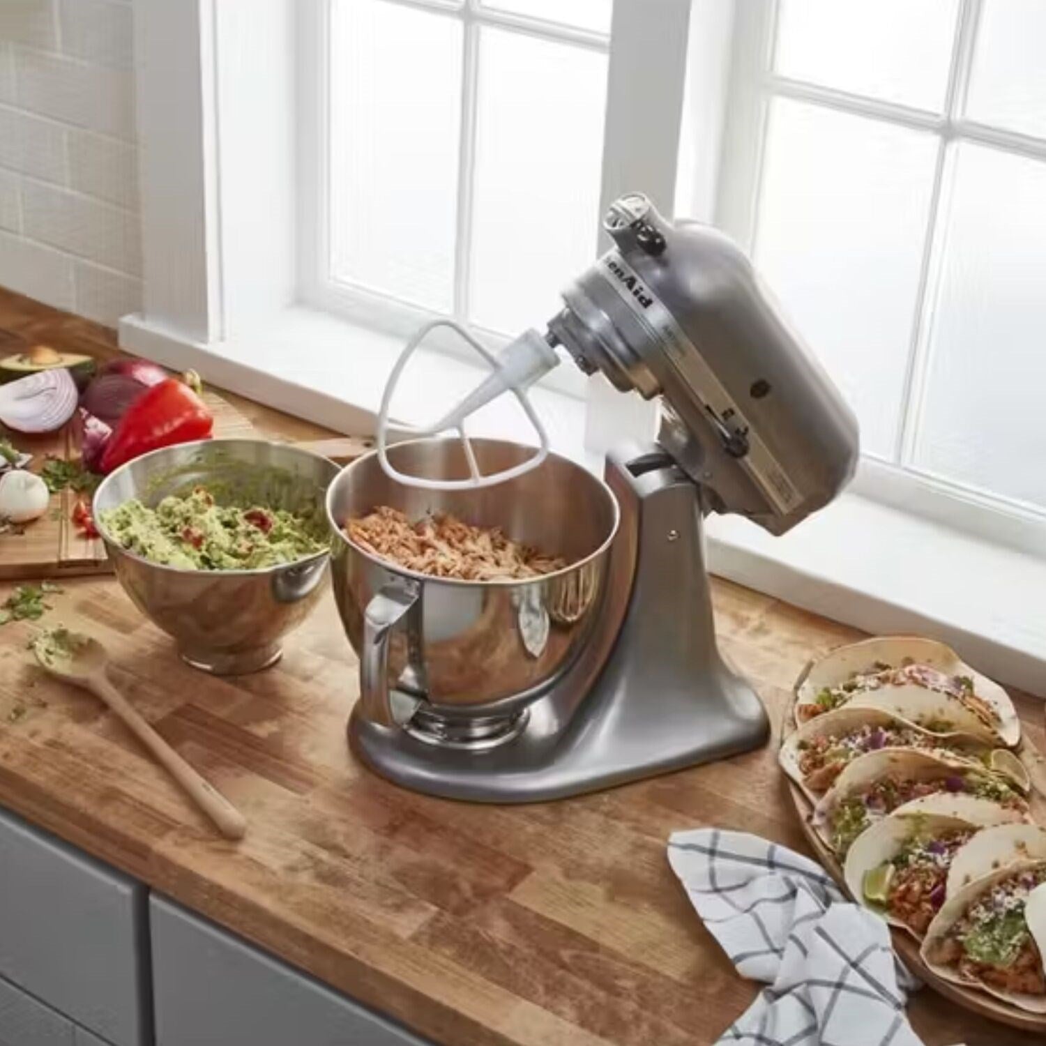 KitchenAid tilt-head stand mixer mixing two bowls of ingredients on countertop