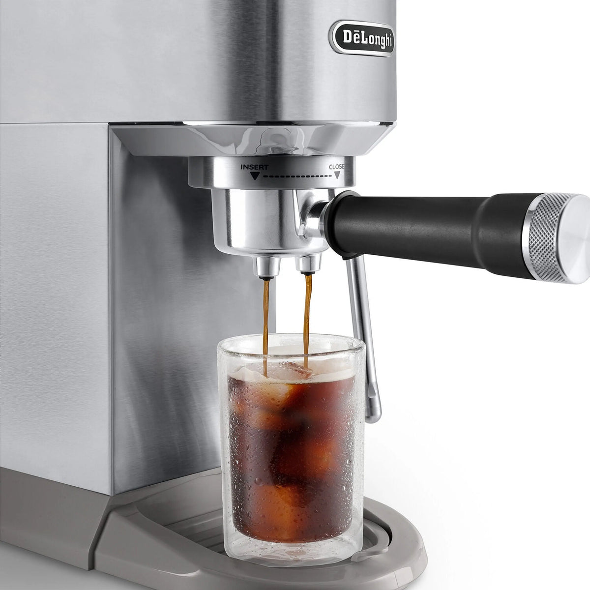 Espresso machine nozzle pouring dark coffee into a clear tall cup
