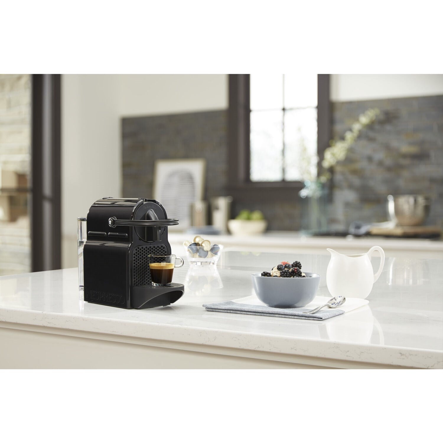 Black espresso machine on countertop with espresso cup and small accessories nearby