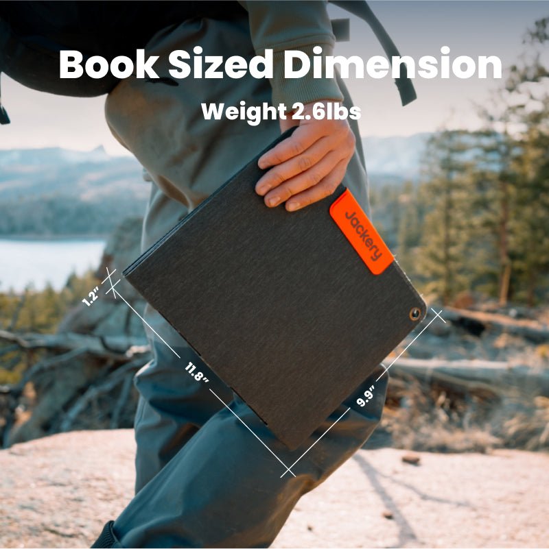 Book-sized portable solar panel held in hand, dark surface with orange Jackery label