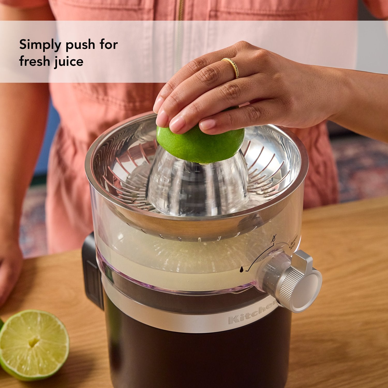 Black citrus juicer with clear strainer as hand presses green lime half