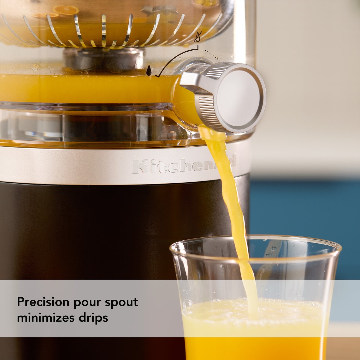 Citrus juicer spout pouring orange juice into a glass