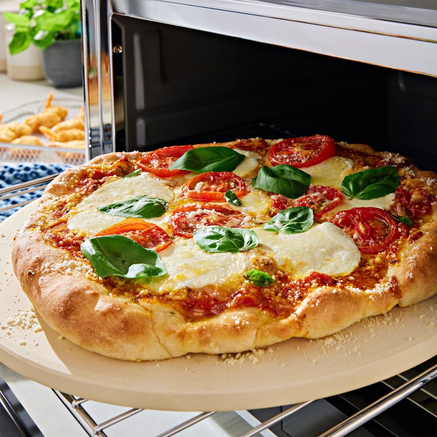 Pizza inside the KitchenAid countertop oven with melted cheese and fresh basil topping