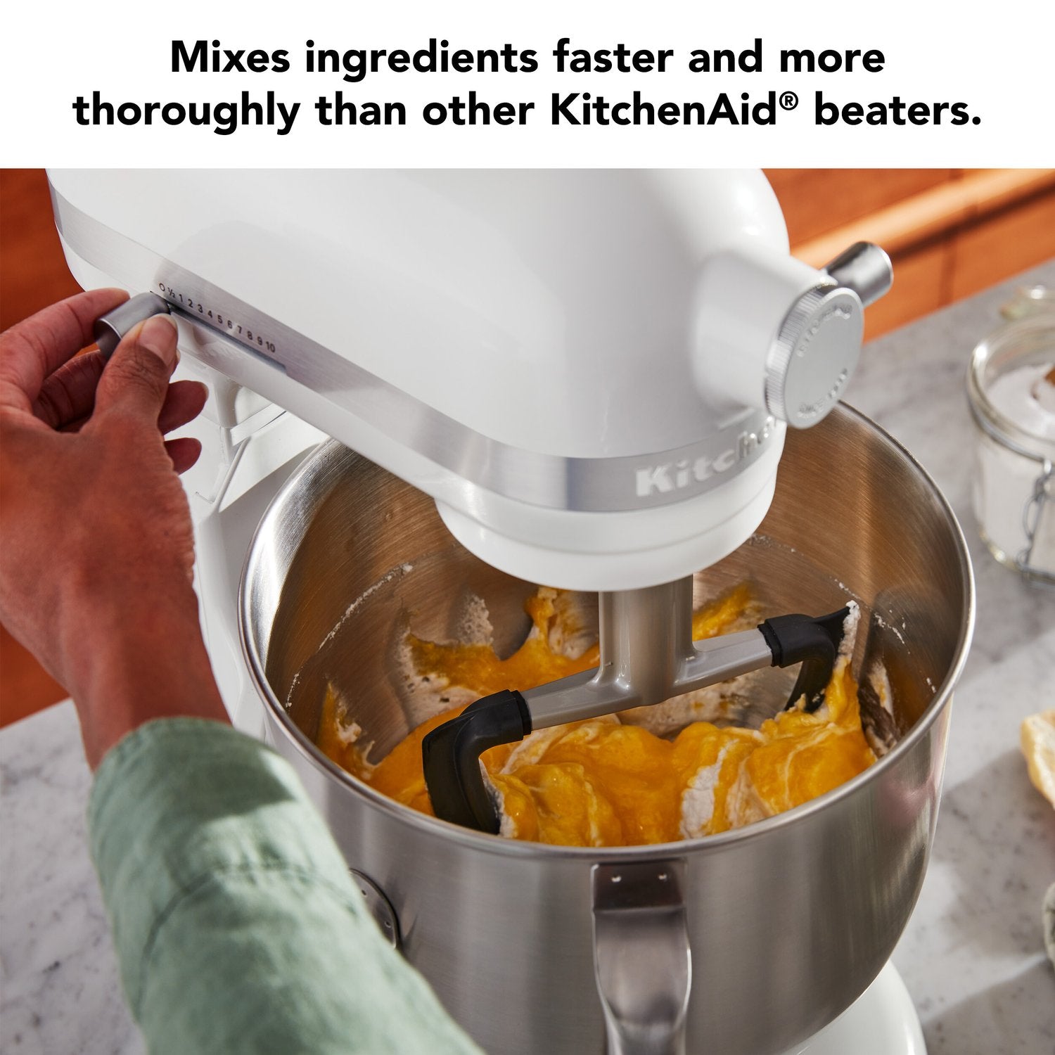 White double flex edge beater attachment spinning in mixing bowl with batter
