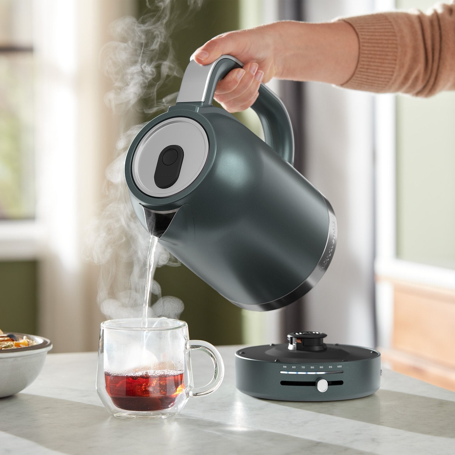 Juniper electric kettle pouring hot water with steam into a glass mug