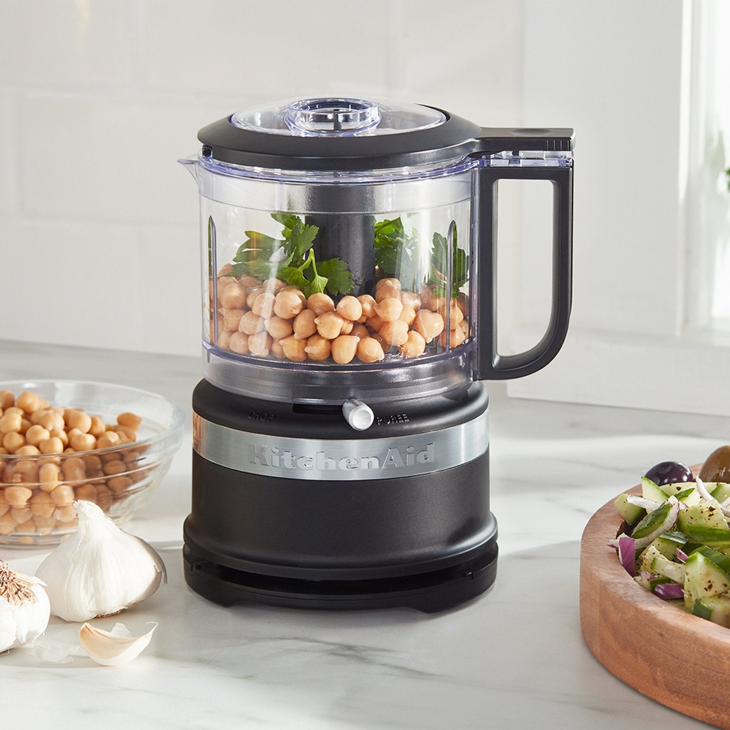 Black matte food chopper with clear bowl and handle, showing chopping ingredients
