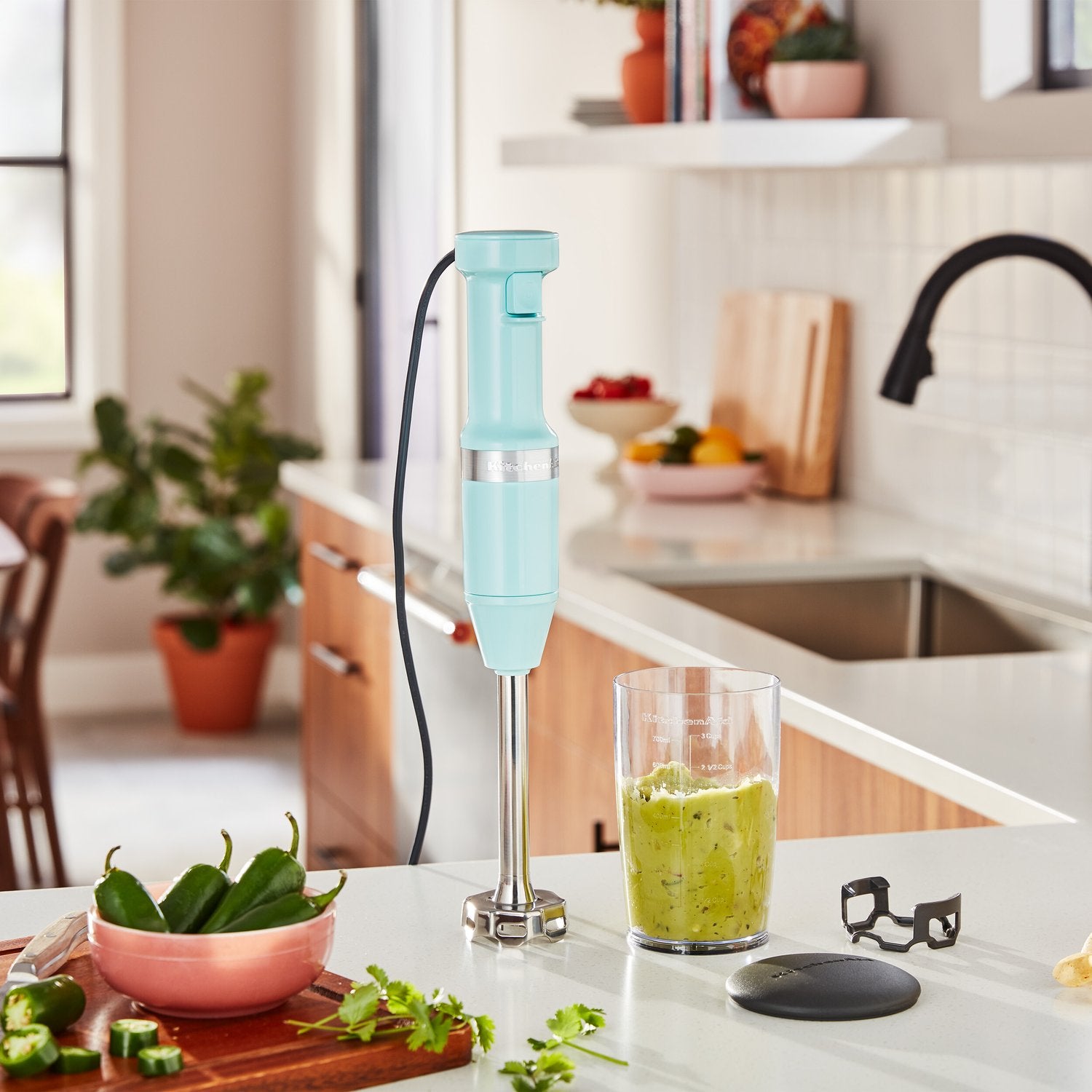 Ice blue immersion blender blending in clear jar with black lid and cord