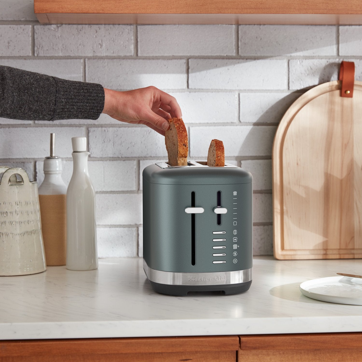 KitchenAid 2-slice toaster in juniper with bread in the slots and side lever down