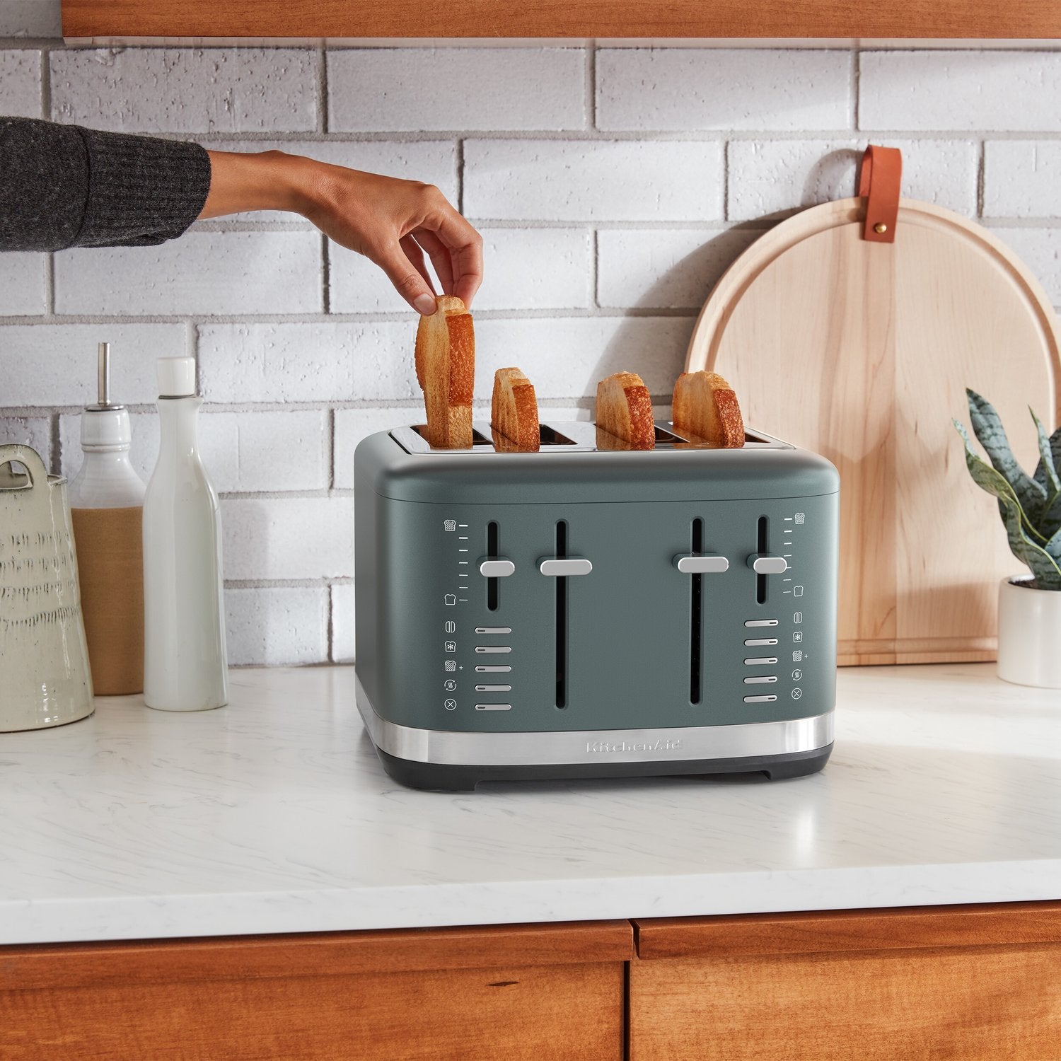 Juniper 4-slice toaster with bread being inserted into slots by hand