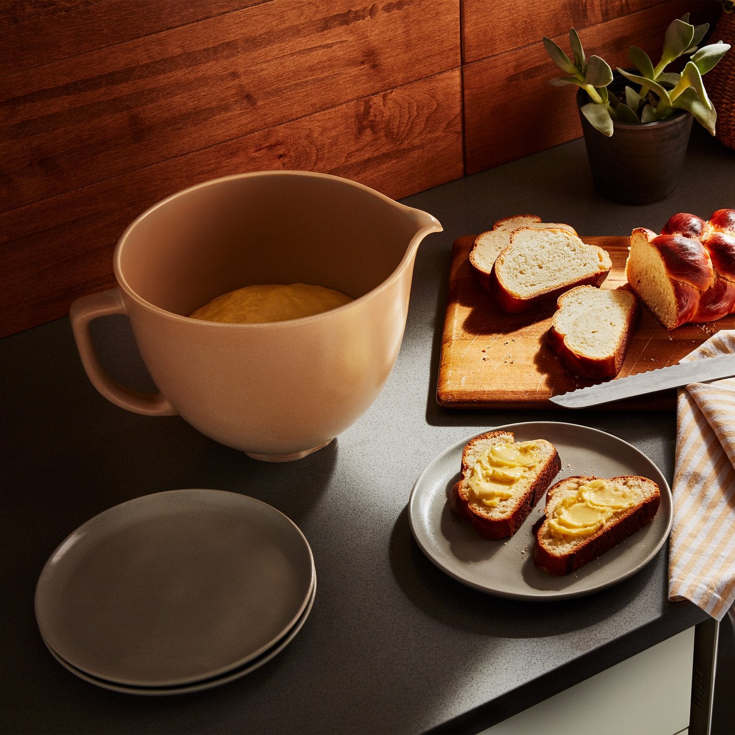 Fired clay tan ceramic mixing bowl next to sliced bread on tray