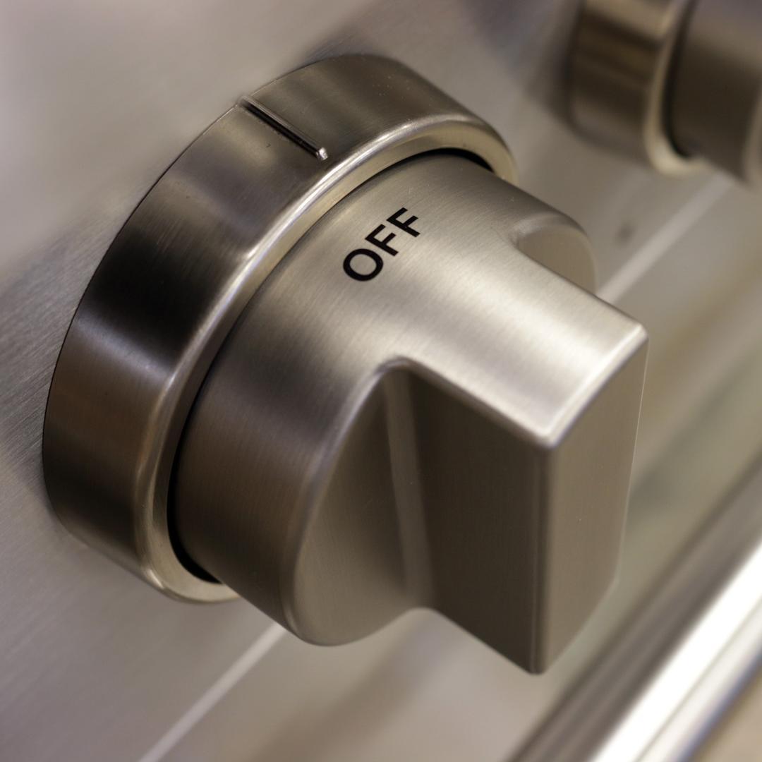 Round stainless steel burner control knob labeled OFF on a gas range