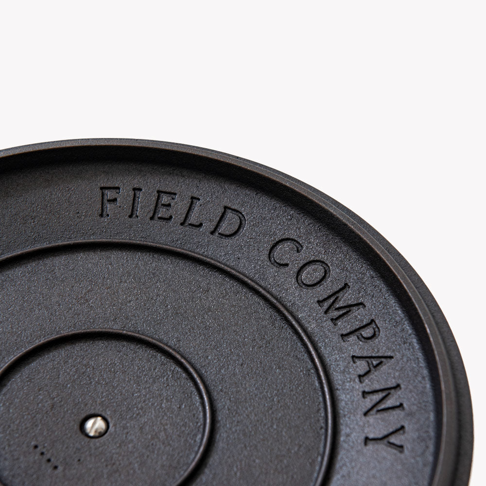 Close-up of embossed lettering on cast iron lid rim, dark charcoal finish