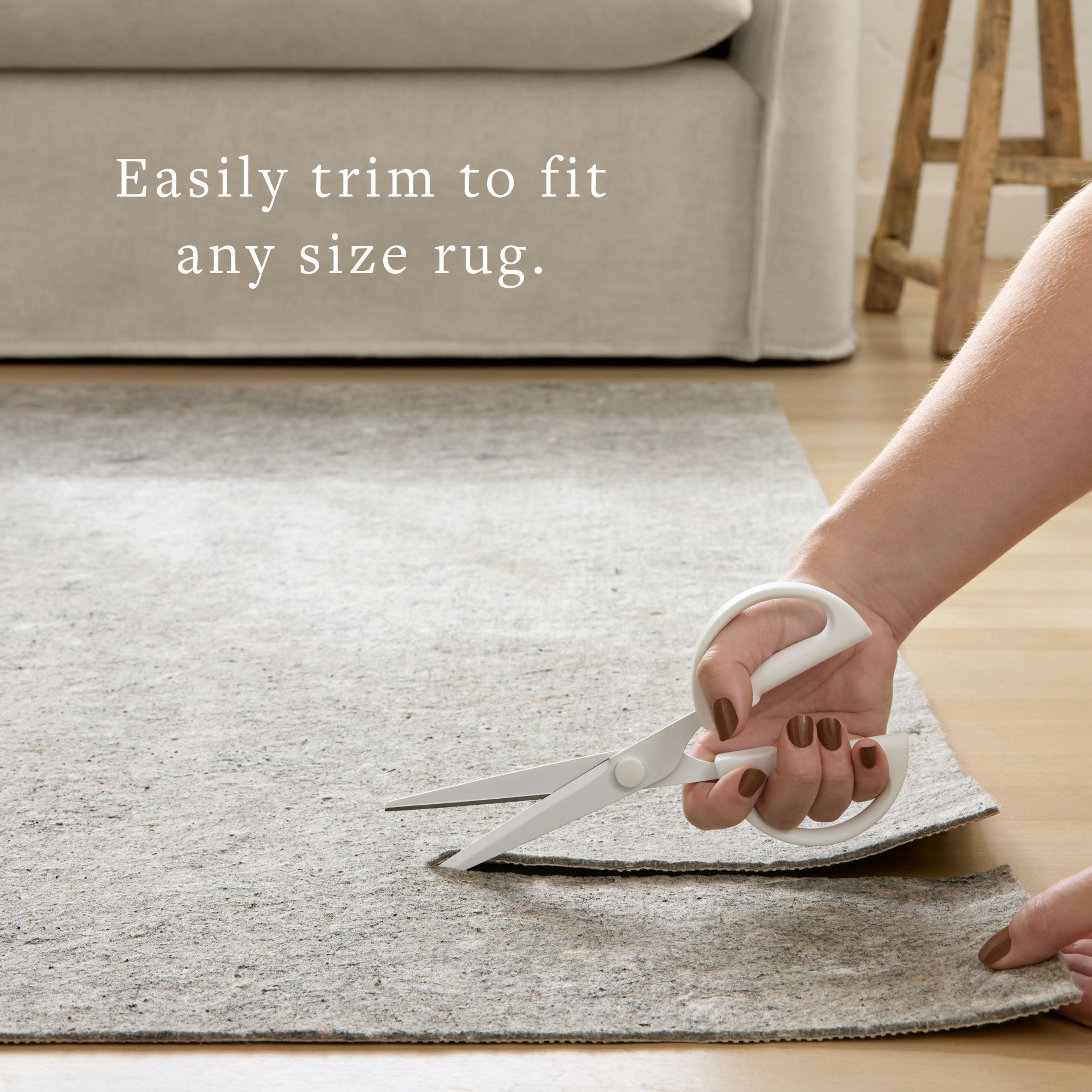 Grey rug pad being trimmed with scissors, grippy felt surface for custom fit