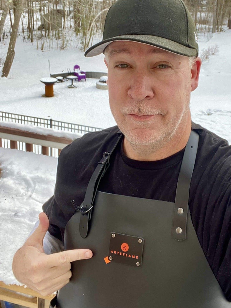 Black leather grill apron with front logo badge and adjustable shoulder straps