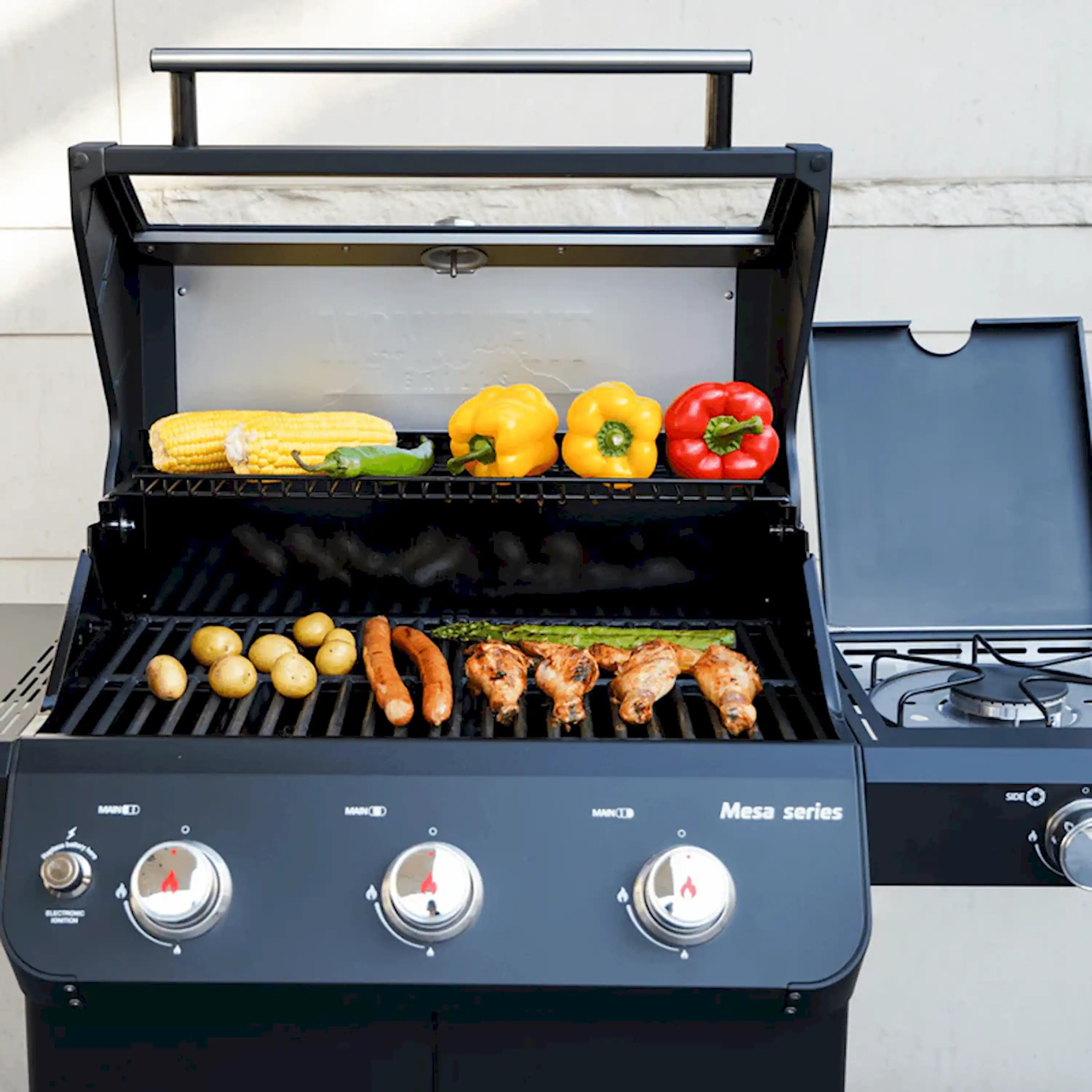 Black 3-burner propane grill with open lid, food on main grates and side rail