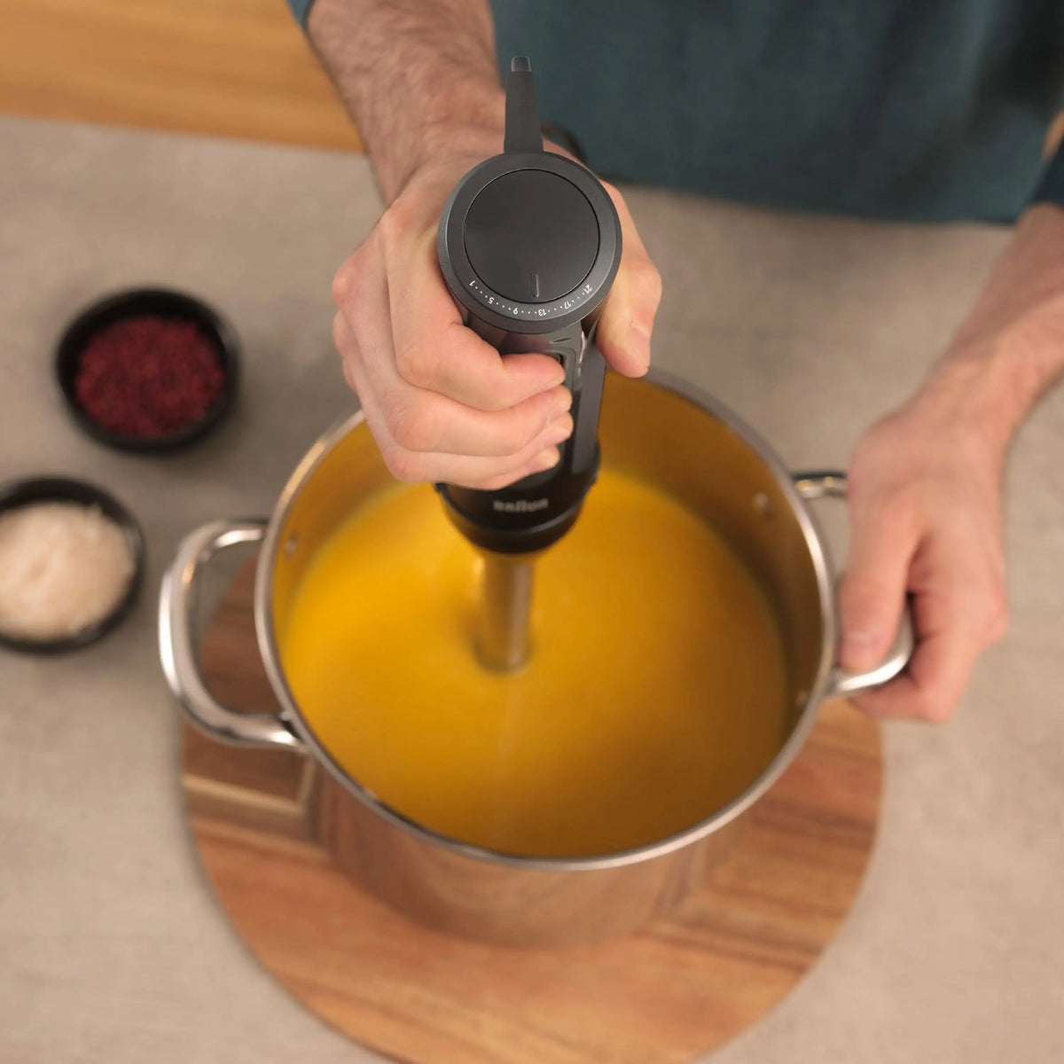 Braun hand blender held above a pot of thick yellow soup