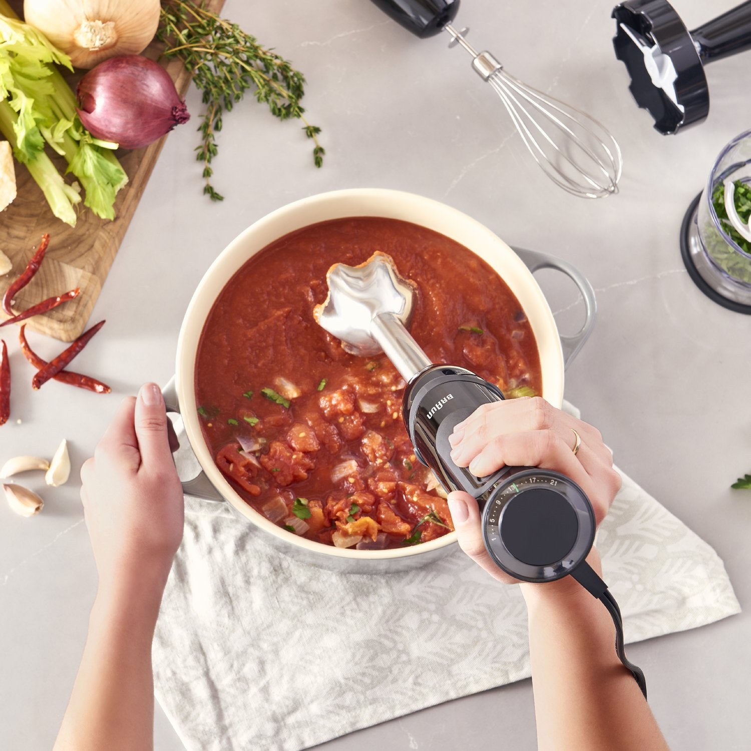 Handheld black Braun blender blending soup in a pot with metal shaft