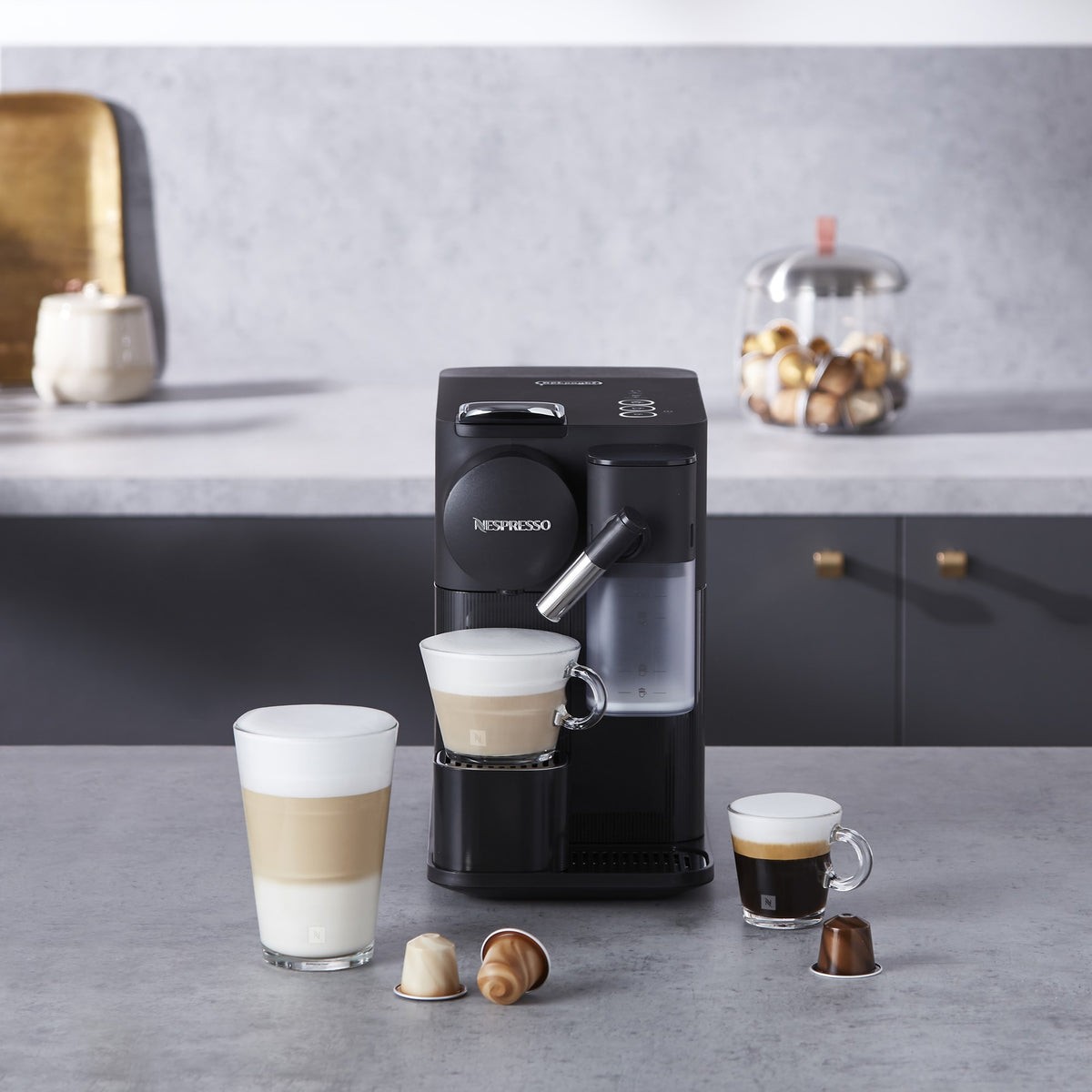 Black Nespresso espresso machine dispensing coffee into a clear glass cup