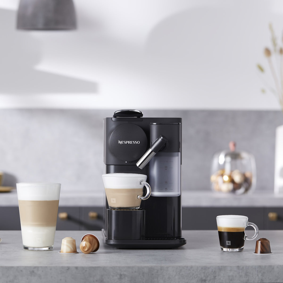 Black espresso machine with two cups and frothing nozzle, with coffee pods