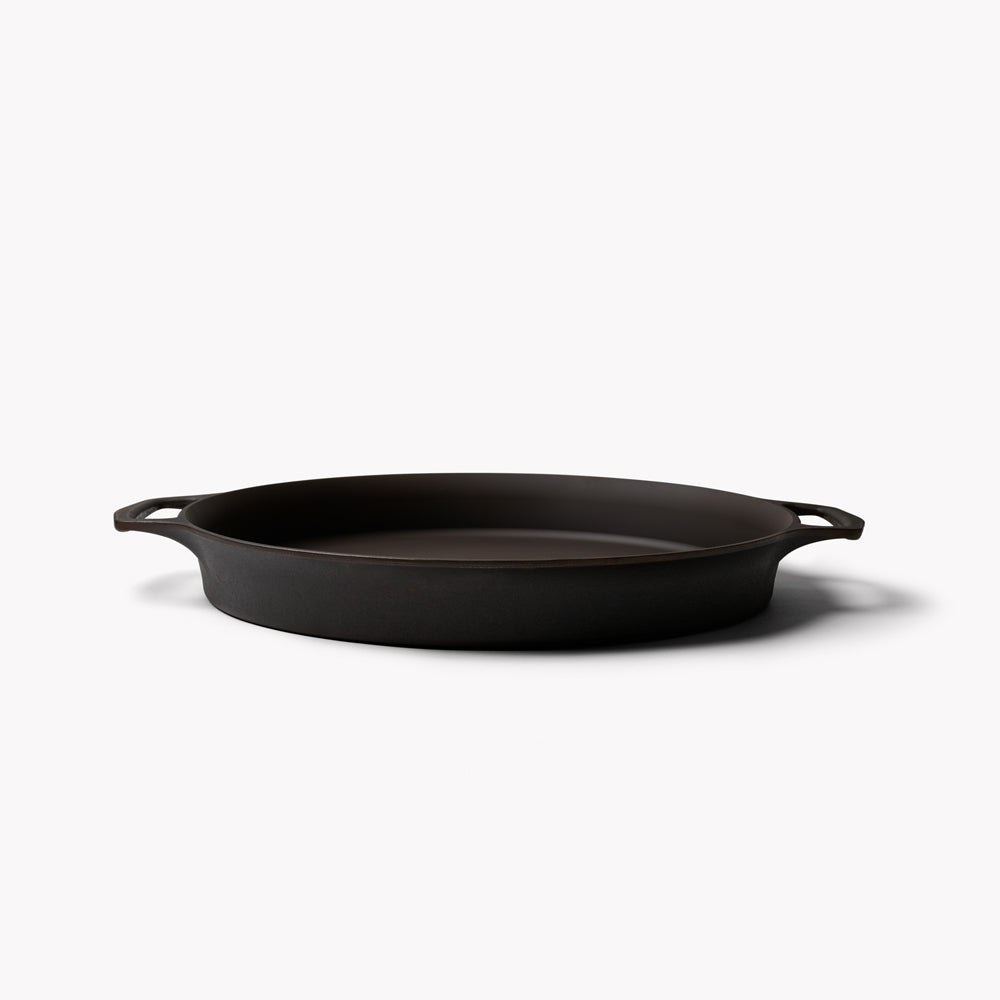 Black cast iron skillet with two loop handles and a low-profile cooking surface