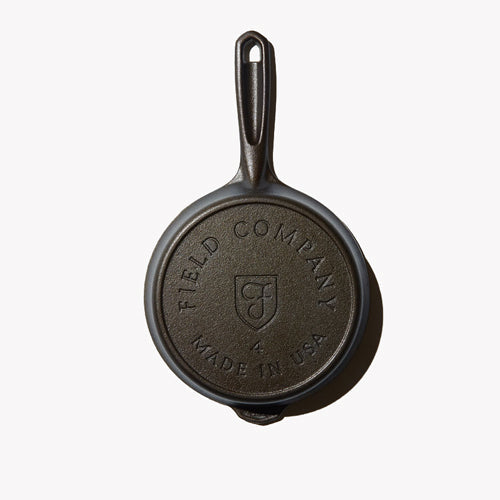 Dark skillet with embossed logo on base, short handle