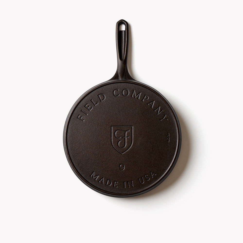 Round cast iron griddle with Field Company logo and hanging handle
