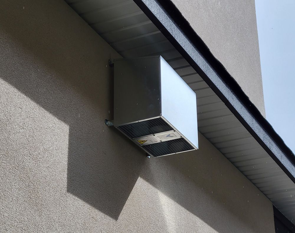 Wall-mounted outdoor blower unit with metal grille and duct vent housing